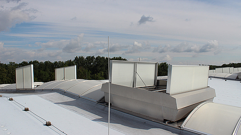 Ventilation systems on an industrial building roof with a cloudy sky in the background
