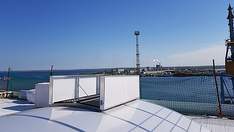 Ventilation system on a roof overlooking an industrial port landscape